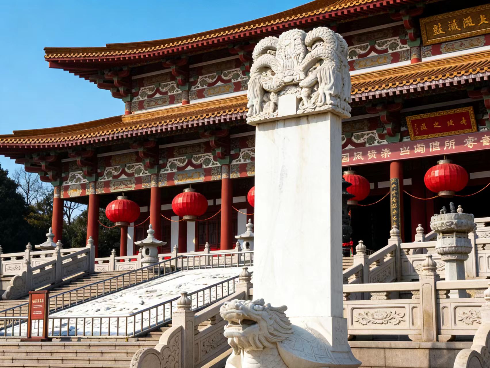 汉白玉赑屃石碑,碑首雕龙纹,背景是重檐歇山顶大殿、石栏与红灯笼